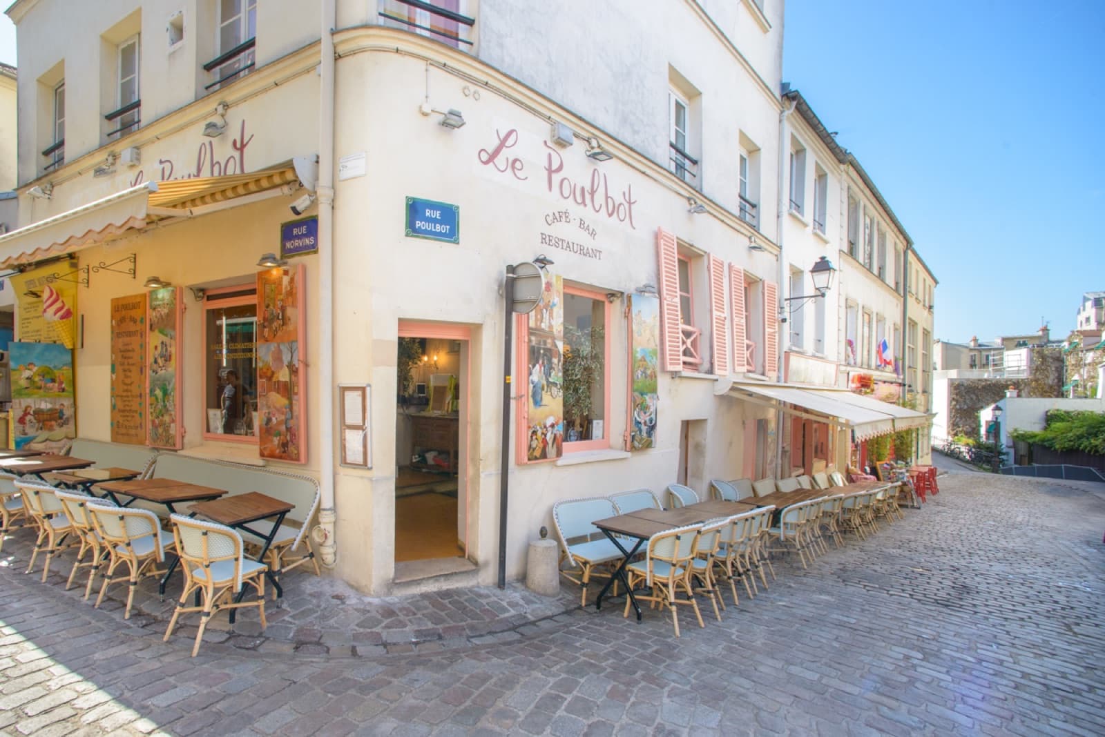Façade de jour du restaurant Le Poulbot avec ses tables en terrasse.