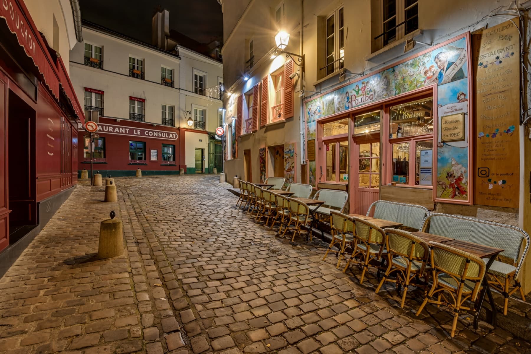 Rue pavée de Montmartre avec la terrasse du restaurant Le Poulbot.
