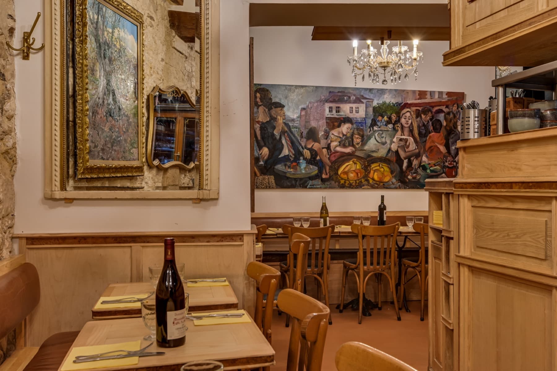 Détail de la salle du Poulbot avec tables dressées, miroir et fresque murale.
