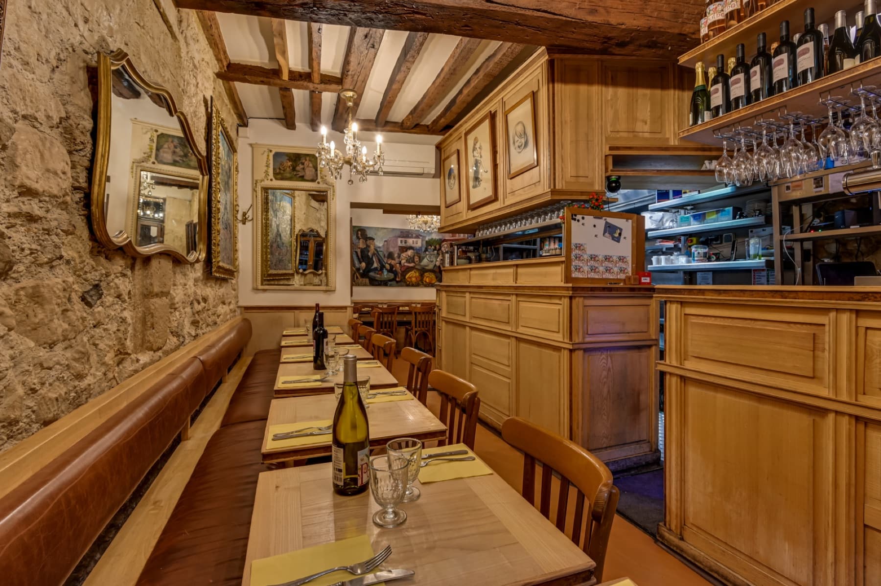 Salle chaleureuse du Poulbot avec murs en pierre, bois clair et tables dressées.